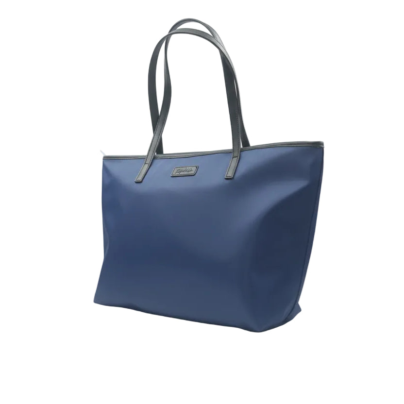 Blue handbag with black handles on a white surface with a glass panel background